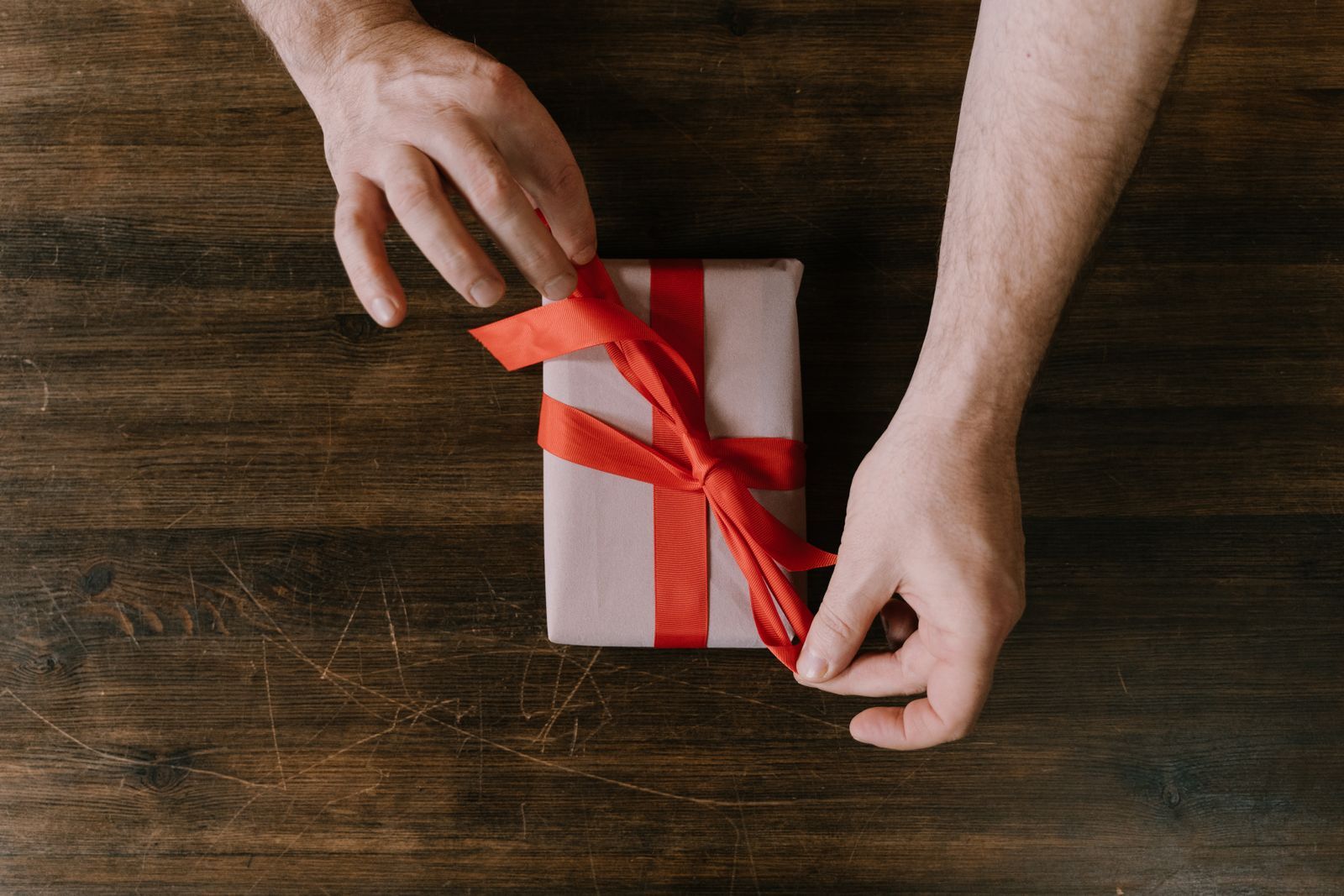 Manos haciendo el moño de un regalo