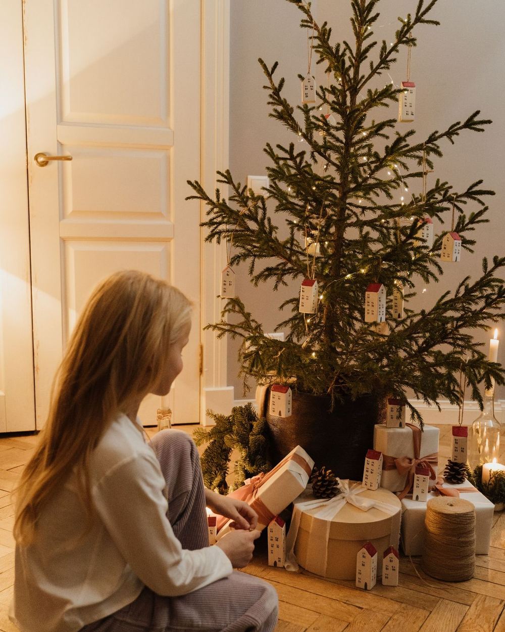 Una niña abre regalos junto al árbol de Navidad